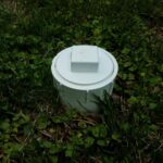 white plastic sewer clean out pipe in green grass