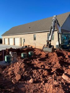 a Cyclone Septics employee uses a Bobcat excavator to backfill around an aerobic septic tank in Shawnee Oklahoma