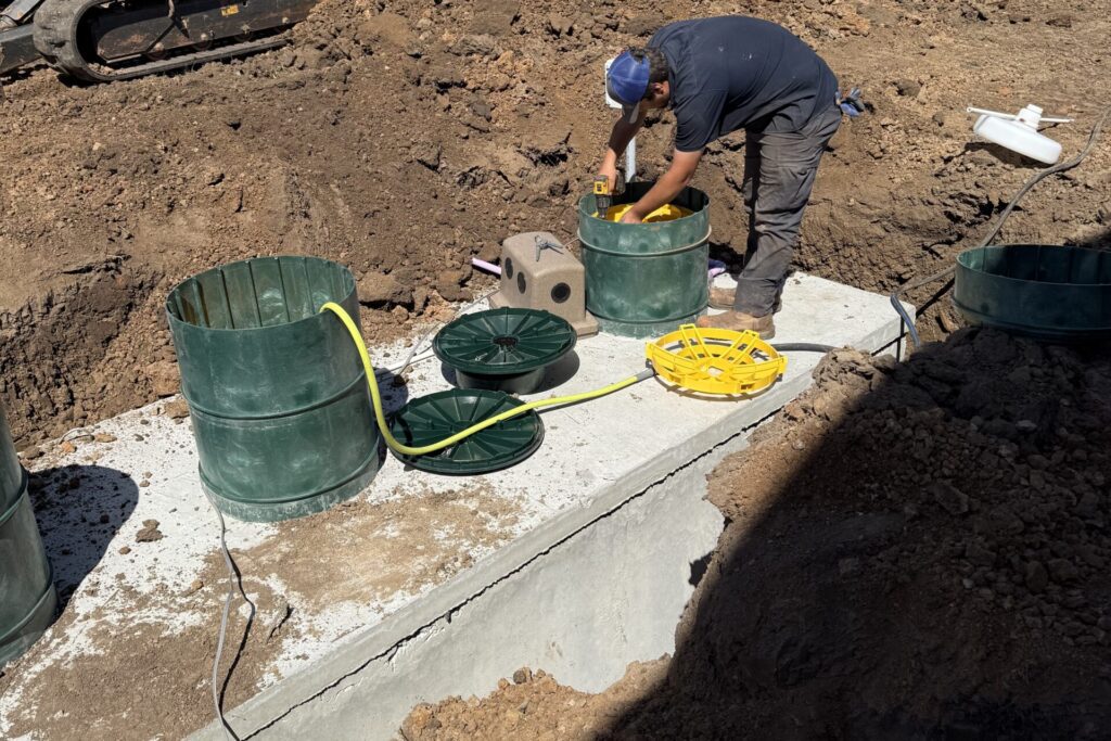 Technician installing aerobic septic system risers at a new home in Edmond, Oklahoma