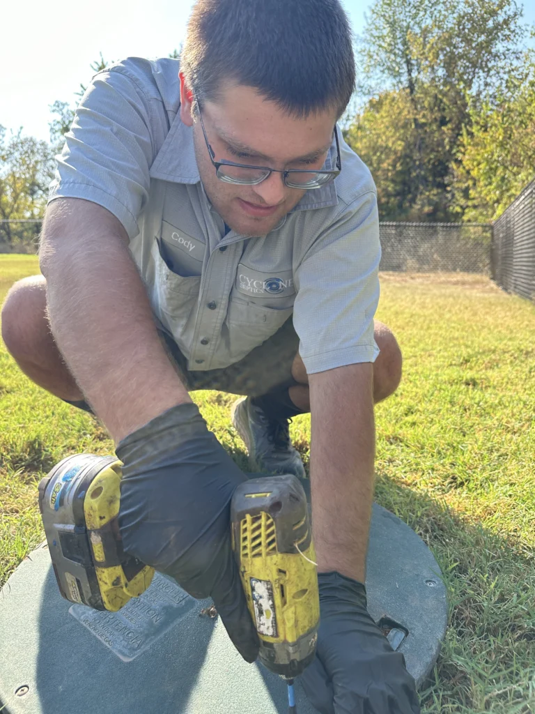 Septic technician inspecting and maintaining a residential septic tank.