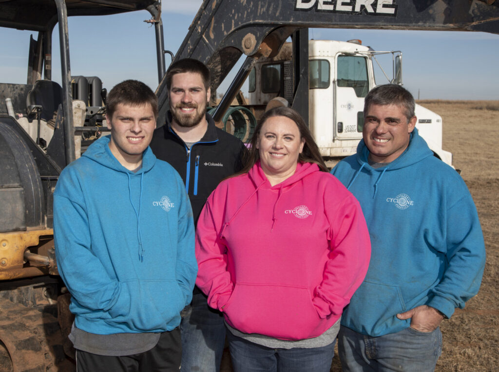 Dawn and Michael Rohrs with their sons, owners of Cyclone Septic & Plumbing, standing in front of an excavator and pump truck in Guthrie, Oklahoma