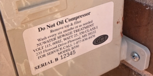 Close-up of a maintenance tag on a beige compressor reading: 'Do Not Oil Compressor' with removal instructions and model/serial details, and a 'GCT' logo nearby.
