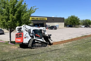Bobcat skid steer trenching for a septic system installation at a Dollar General commercial property.