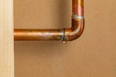 Close-up of copper pipe with a water leak at the joint, Cyclone Septics leak detection and pipe repair service in Oklahoma.