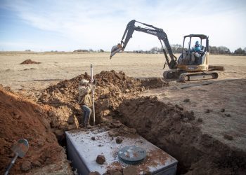 septic installation A worker from Cyclone Septics uses a laser transit to check the depth of a trench being dug by a septic installer for Cyclone Septics