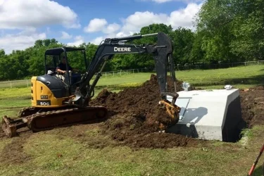 Excavator installing a concrete storm shelter in Oklahoma yard
