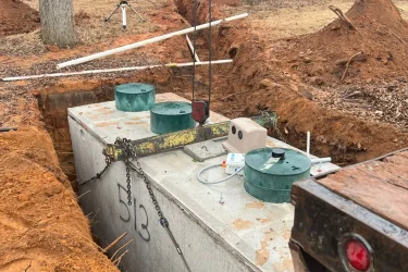 Precast concrete septic tank being lowered into a trench during installation on a Jones, OK property