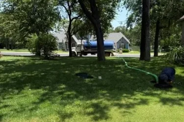 Technician pumping a septic tank through open risers at a home in Jones, OK